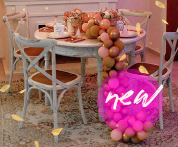 Mesa festiva con globos en tonalidades rosa, sillas de madera